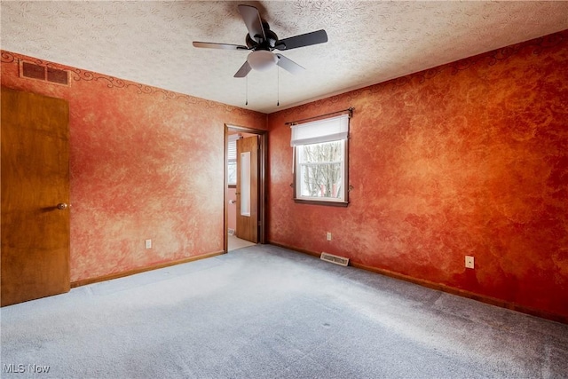 carpeted spare room with a textured ceiling and ceiling fan