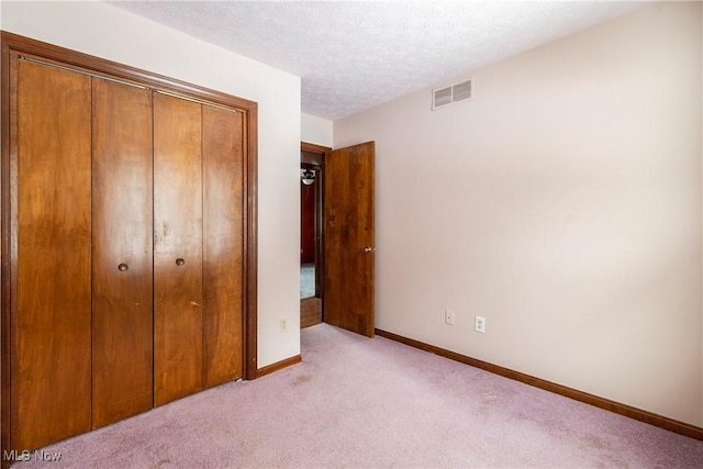 unfurnished bedroom featuring light colored carpet, a closet, and a textured ceiling