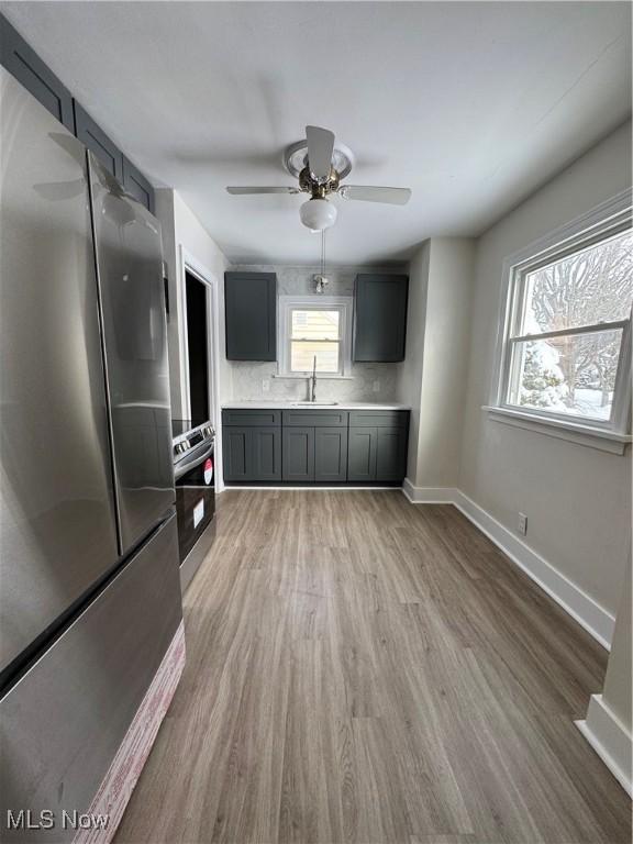 kitchen with ceiling fan, light hardwood / wood-style floors, decorative backsplash, sink, and stainless steel appliances