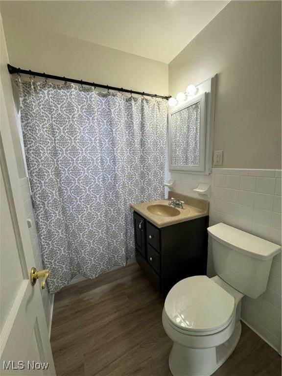 bathroom featuring toilet, vanity, tile walls, and hardwood / wood-style flooring