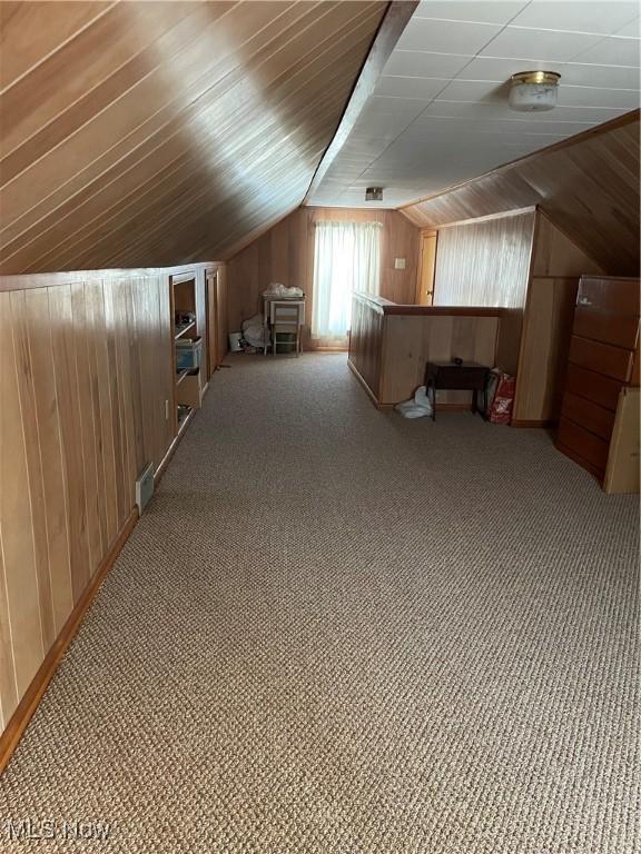 bonus room featuring lofted ceiling and wooden walls