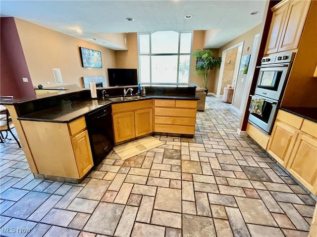 kitchen featuring dishwasher, double oven, an island with sink, light brown cabinetry, and sink