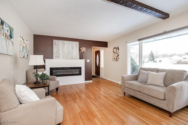 living room featuring hardwood / wood-style flooring, beam ceiling, and a brick fireplace