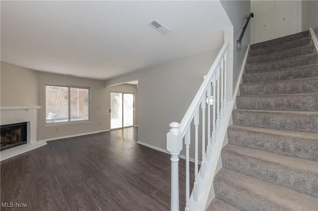 staircase featuring hardwood / wood-style flooring and a fireplace