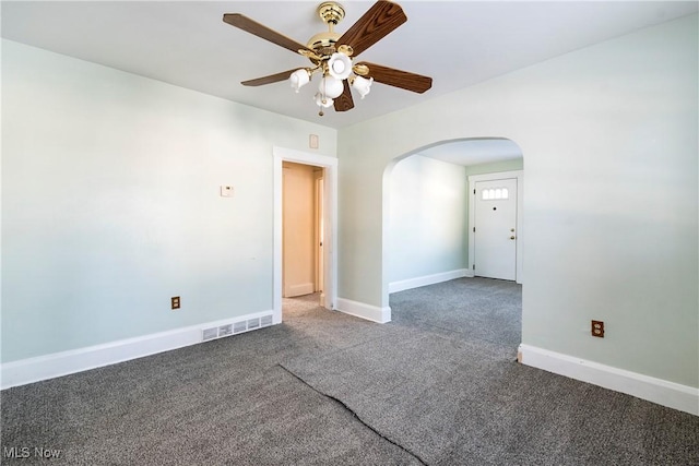 spare room featuring dark colored carpet and ceiling fan