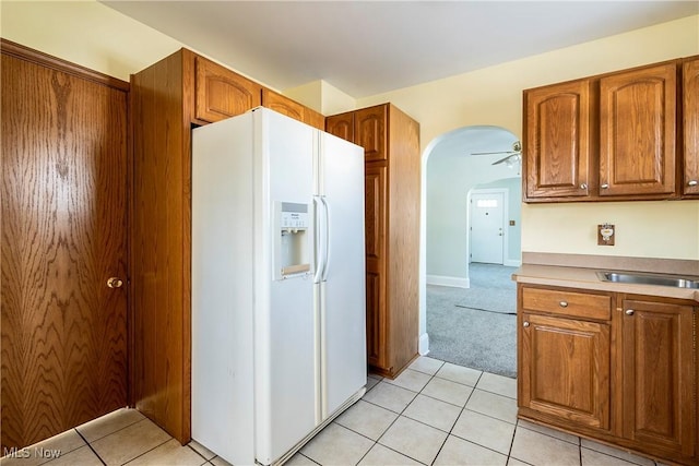 kitchen featuring ceiling fan, white fridge with ice dispenser, and light tile patterned floors