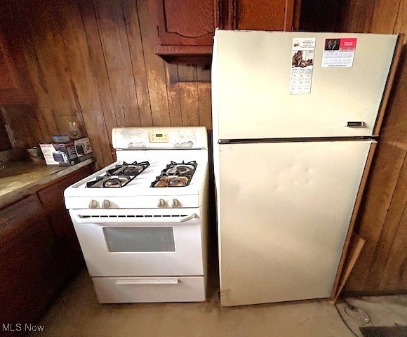 kitchen with white appliances and wooden walls