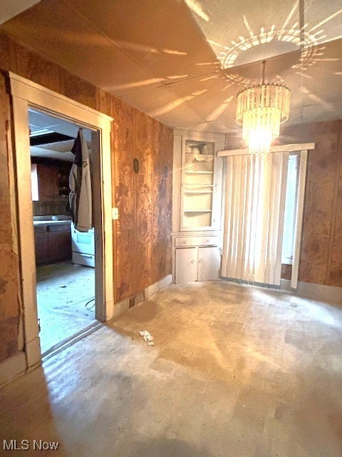 empty room featuring wood walls and concrete flooring