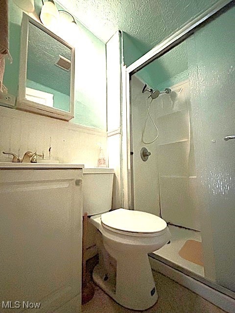 bathroom with backsplash, a textured ceiling, toilet, and walk in shower