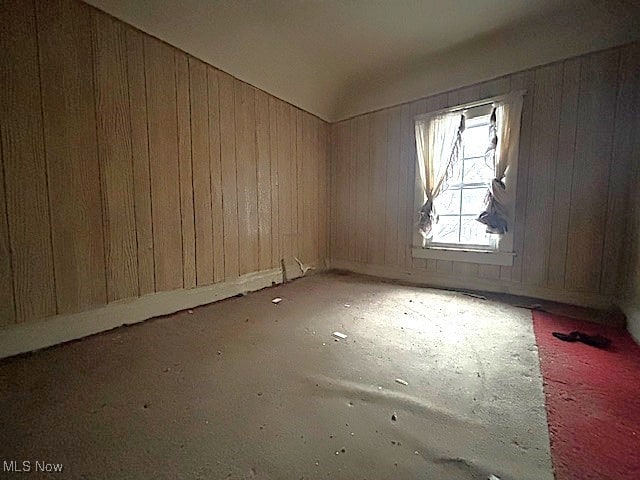 unfurnished room featuring wooden walls