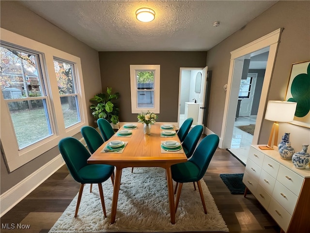 dining space featuring a healthy amount of sunlight, dark hardwood / wood-style flooring, and a textured ceiling