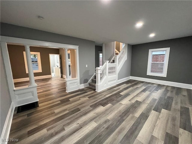 unfurnished living room with dark wood-type flooring and decorative columns