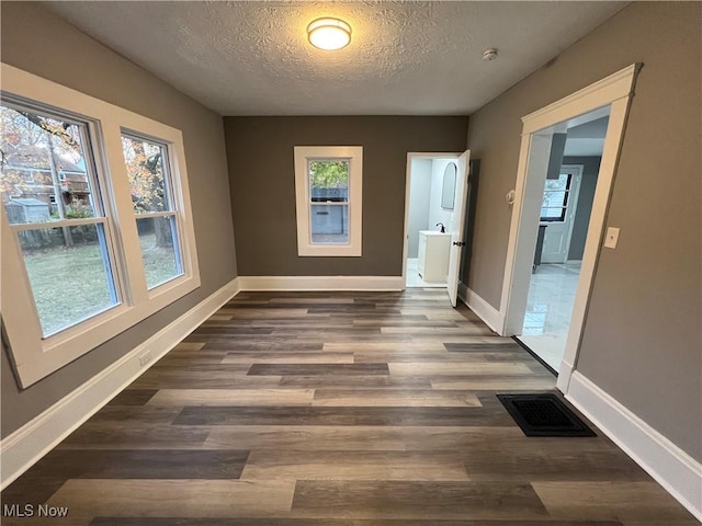 unfurnished room featuring dark wood-type flooring and a textured ceiling