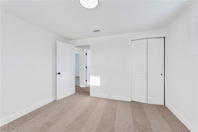 unfurnished bedroom with carpet floors, a closet, and a textured ceiling