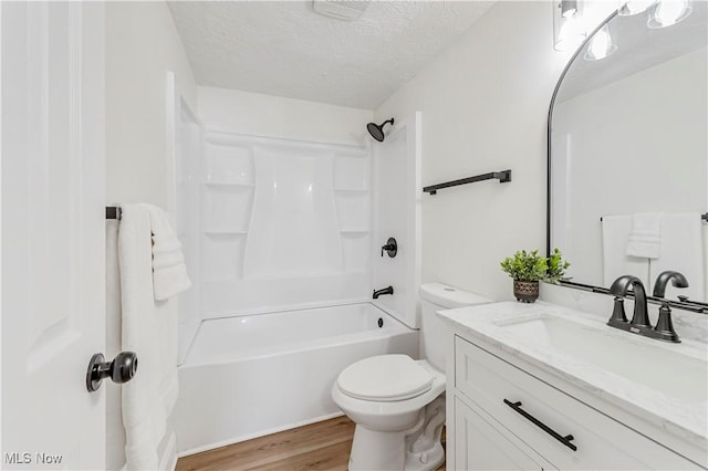 full bathroom featuring toilet, hardwood / wood-style flooring, washtub / shower combination, a textured ceiling, and vanity