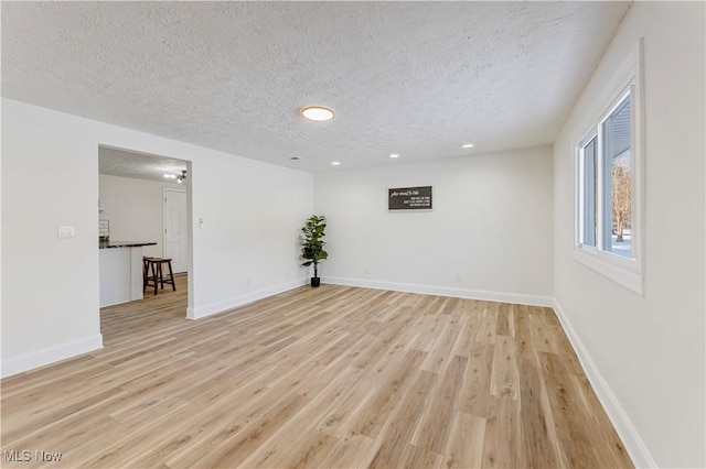 unfurnished room featuring light hardwood / wood-style floors and a textured ceiling