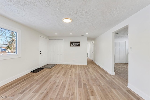 empty room with light wood-type flooring and a textured ceiling