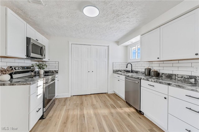 kitchen featuring stainless steel appliances, backsplash, white cabinets, and sink