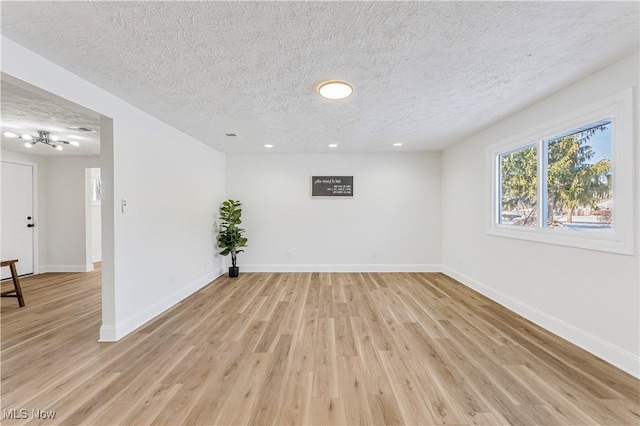 spare room featuring light wood-type flooring and a textured ceiling