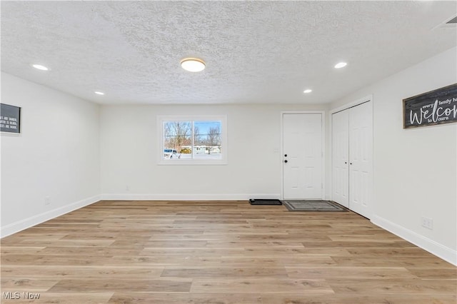 basement featuring a textured ceiling and light hardwood / wood-style flooring