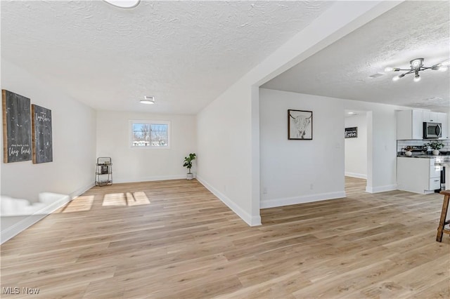 unfurnished living room featuring light wood-type flooring and a textured ceiling