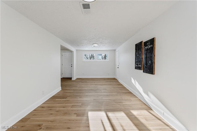 empty room featuring a textured ceiling and light hardwood / wood-style floors