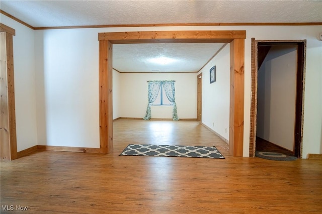 hall with crown molding, a textured ceiling, and hardwood / wood-style floors