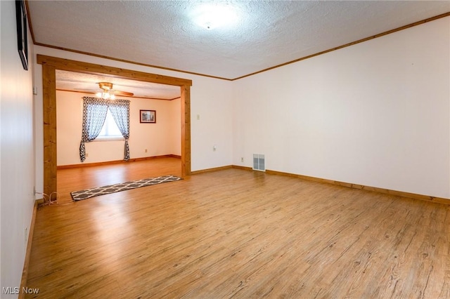 spare room with a textured ceiling, crown molding, and hardwood / wood-style floors