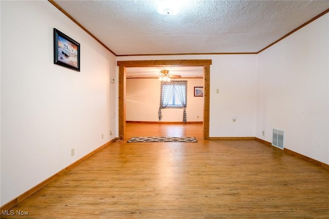 empty room featuring ceiling fan, light wood-type flooring, ornamental molding, and a textured ceiling