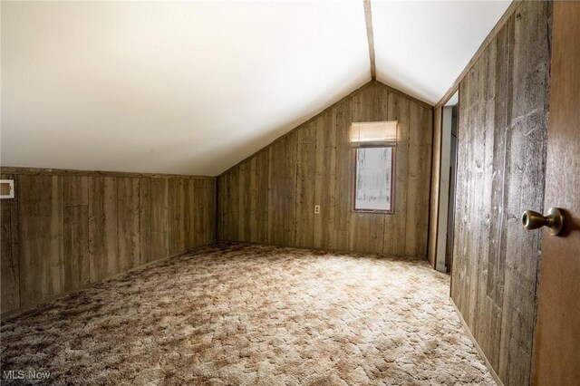 additional living space featuring light colored carpet, lofted ceiling, and wooden walls