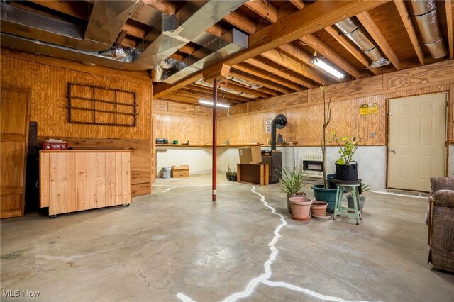 interior space featuring a wood stove, heating unit, and wood walls