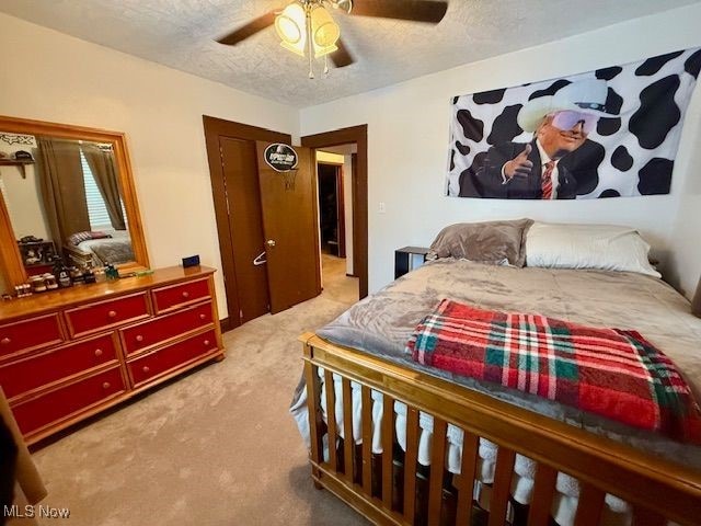 bedroom featuring a textured ceiling, ceiling fan, and light colored carpet