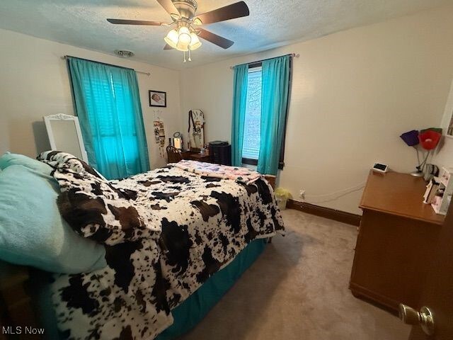 bedroom featuring a textured ceiling, ceiling fan, and carpet floors