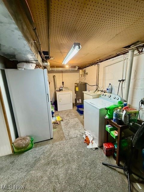 basement featuring washing machine and dryer, sink, and water heater