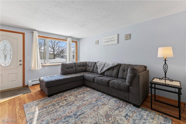 living room featuring a baseboard heating unit, a textured ceiling, and hardwood / wood-style flooring