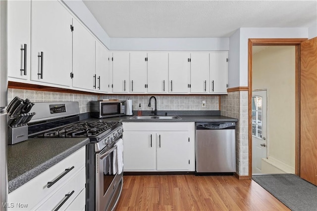 kitchen with light hardwood / wood-style floors, decorative backsplash, sink, stainless steel appliances, and white cabinets