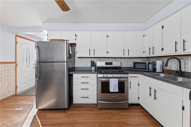 kitchen featuring dark wood-type flooring, white cabinetry, stainless steel appliances, sink, and ceiling fan