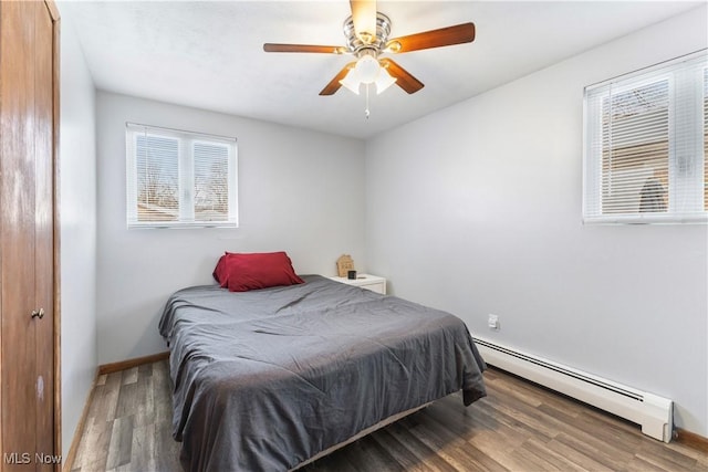 bedroom with a baseboard heating unit, ceiling fan, and wood-type flooring