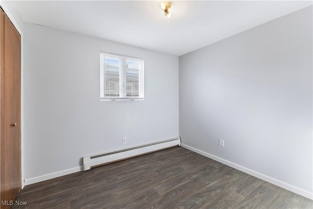 spare room with dark wood-type flooring and baseboard heating