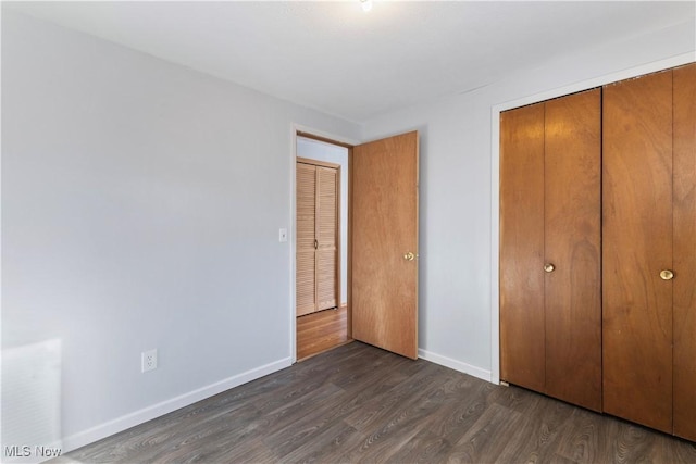 unfurnished bedroom featuring a closet and dark wood-type flooring