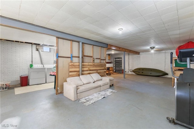 basement featuring brick wall and separate washer and dryer