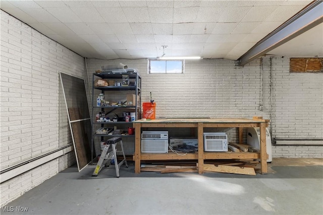 basement featuring a wall mounted AC, a workshop area, brick wall, and a baseboard heating unit