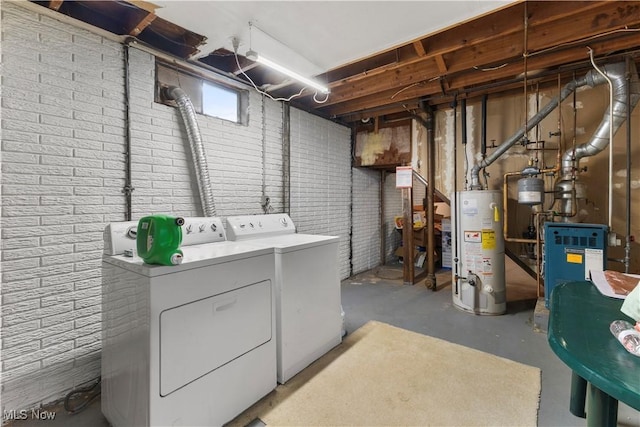 clothes washing area with water heater, brick wall, and washing machine and clothes dryer