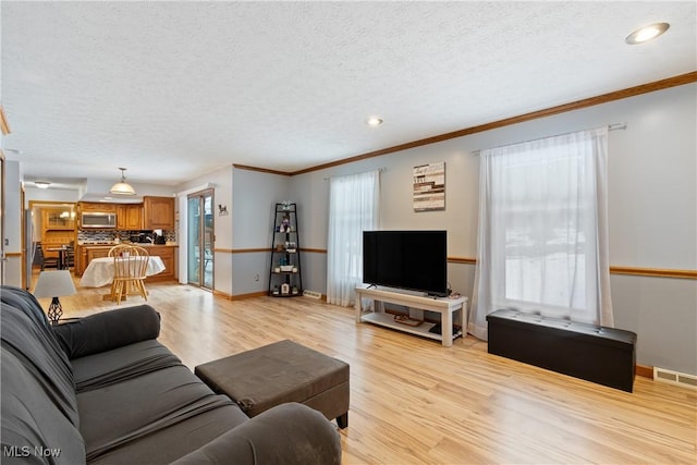 living room featuring a textured ceiling, crown molding, and light hardwood / wood-style flooring