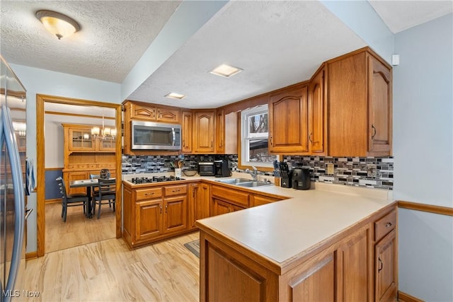 kitchen featuring stainless steel appliances, backsplash, kitchen peninsula, and sink