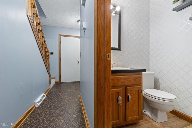 bathroom with toilet, a textured ceiling, and vanity