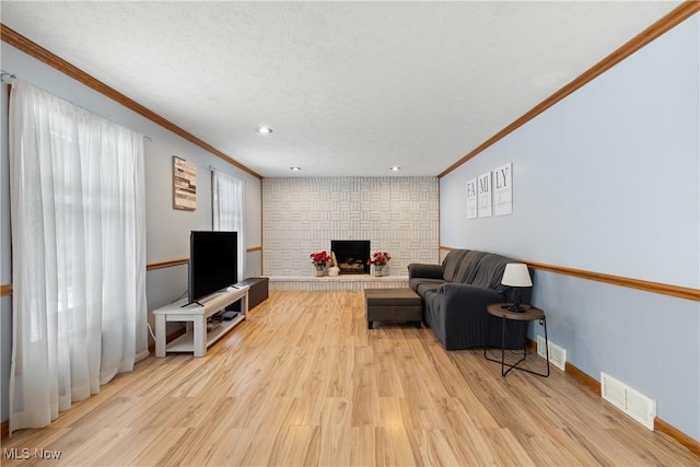 living room with a large fireplace, light hardwood / wood-style floors, and ornamental molding