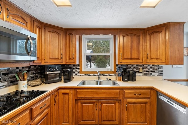 kitchen with sink, a textured ceiling, backsplash, and stainless steel appliances