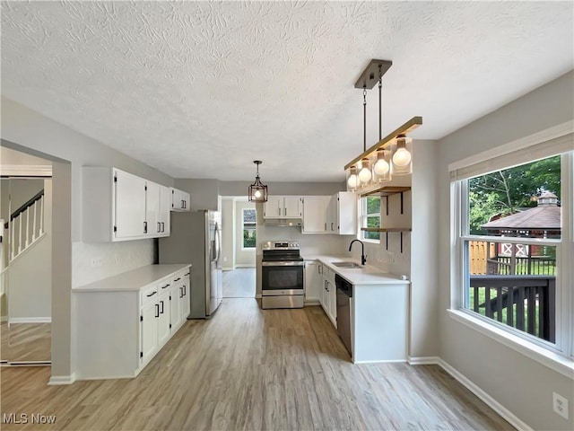 kitchen featuring sink, hanging light fixtures, plenty of natural light, stainless steel appliances, and white cabinets