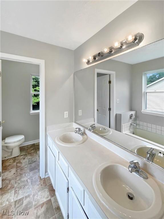 bathroom with toilet, vanity, and a tub